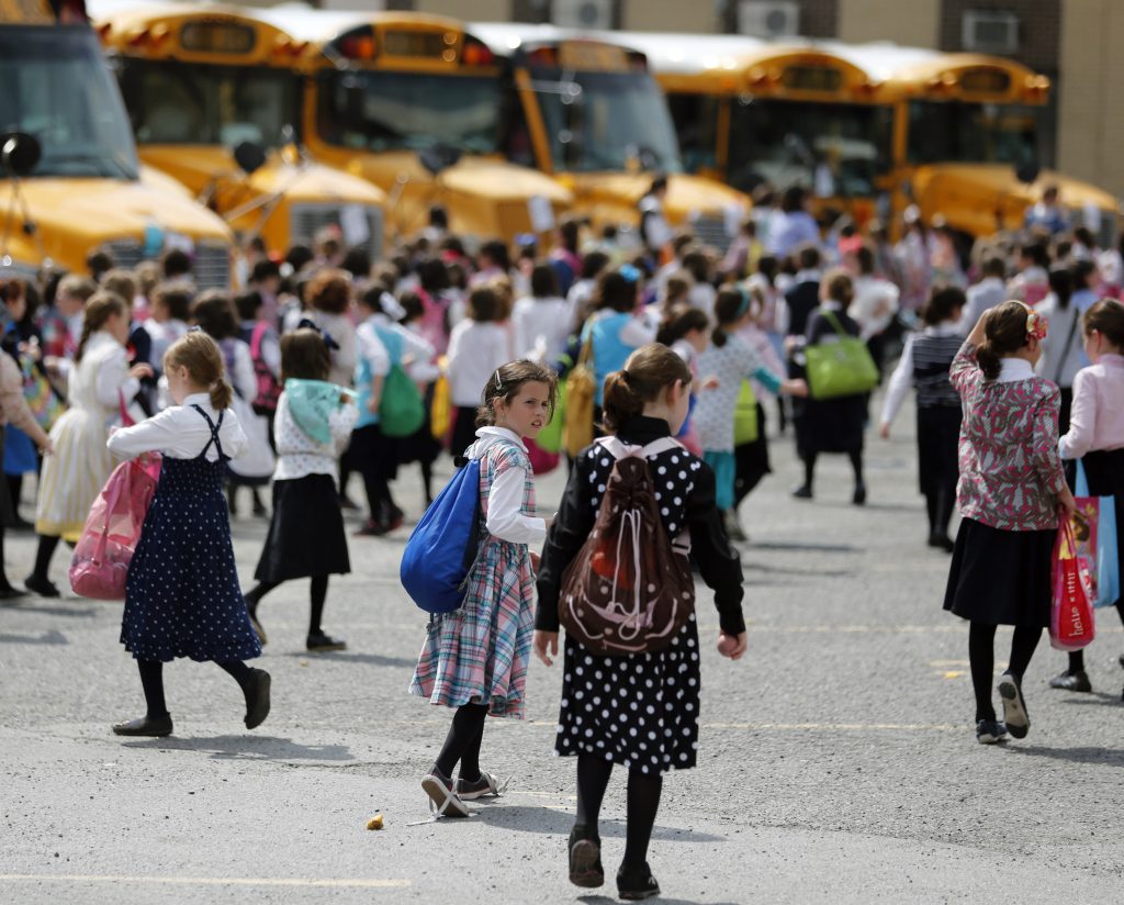 Measles Summer Camp In this July 1, 2014 file photo, Orthodox Jewish girls walk to waiting buses after summer day camp in Kiryas Joel, N.Y. Kiryas Joel is a tightly packed Hasidic enclave surrounded by suburbia in the Hudson Valley. As a measles outbreak stretches toward summer camp season, New York counties with a concentration of Orthodox Jewish camps are requiring vaccinations for campers and staff. (Mike Groll/AP Photo)