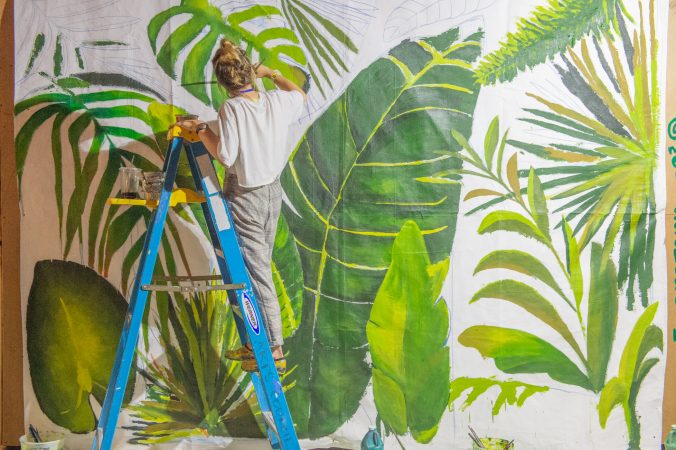 Princeton-based multimedia artist Melissa Kuscin works on a collaborative mural that she invited members of the public to help paint. (Jonathan Wilson for WHYY)