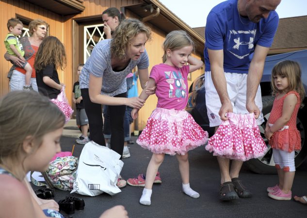 Val Rutherford (left) helps her daughter, Brenna Rutherford, put on a skirt as members of the Miller Family practice their hoedown routine. (Matt Smith for WHYY)