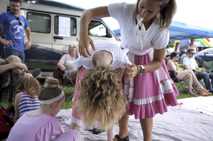 Sophie Rutherford (left) has her hair fluffed out by her aunt, Kelsea Rutherford, as they get ready for a performance of the Miller Family Hoedown. (Matt Smith for WHYY)