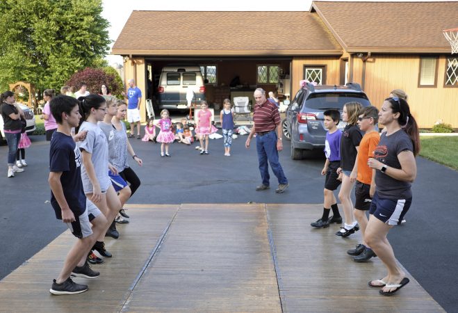 Members of the Miller family practice their hoedown routine on a portable dance floor in the driveway of the home of Lester Miller in Kutztown, Pennsylvania. (Matt Smith for WHYY)