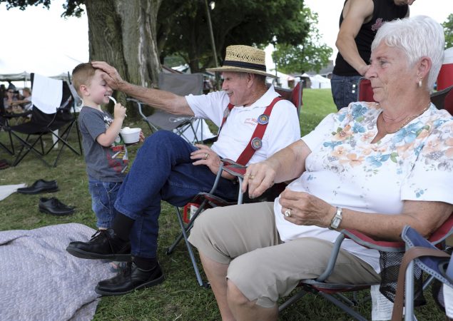 Kody Rutherford (left) interacts with his great-grandfather Lester Miller (center) and great-grandmother Faye Miller (right) as they rest between performances. (Matt Smith for WHYY)