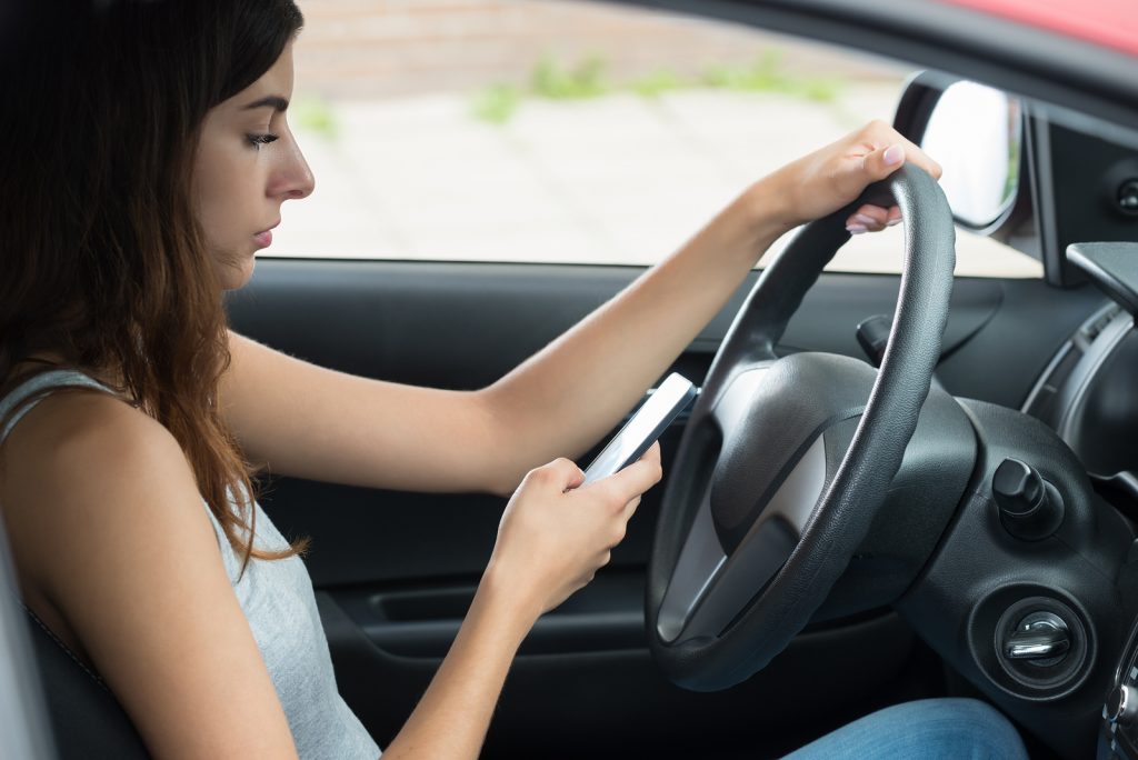 Side View Of Young Woman Using Mobile Phone While Driving Car Side View Of Young Woman Using Mobile Phone While Driving Car