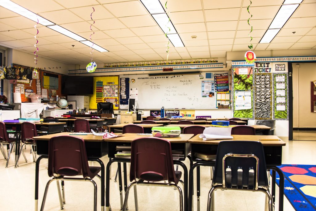 bigstock–174690289 School concept. Back to school, School classroom with empty school chairs and tables, classroom without students, School supplies on blackboard, School of Schoolchild and student education.