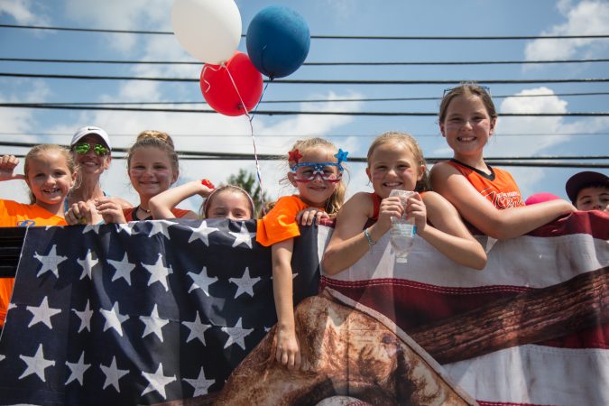 Members of South Marple Little League wave and throw candy at the members of their community who have lined up along the two-mile parade route. (Emily Cohen for WHYY)