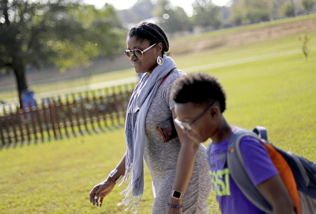 Corrie Davis In this Oct. 11, 2017 file photo, Corrie Davis, left, picks up her son Turner from Big Shanty Elementary School in Kennesaw, Ga. The previous month, the school invited fifth-graders to dress up as characters from the Civil War. Davis says a white student dressed as a plantation owner approached her son and said