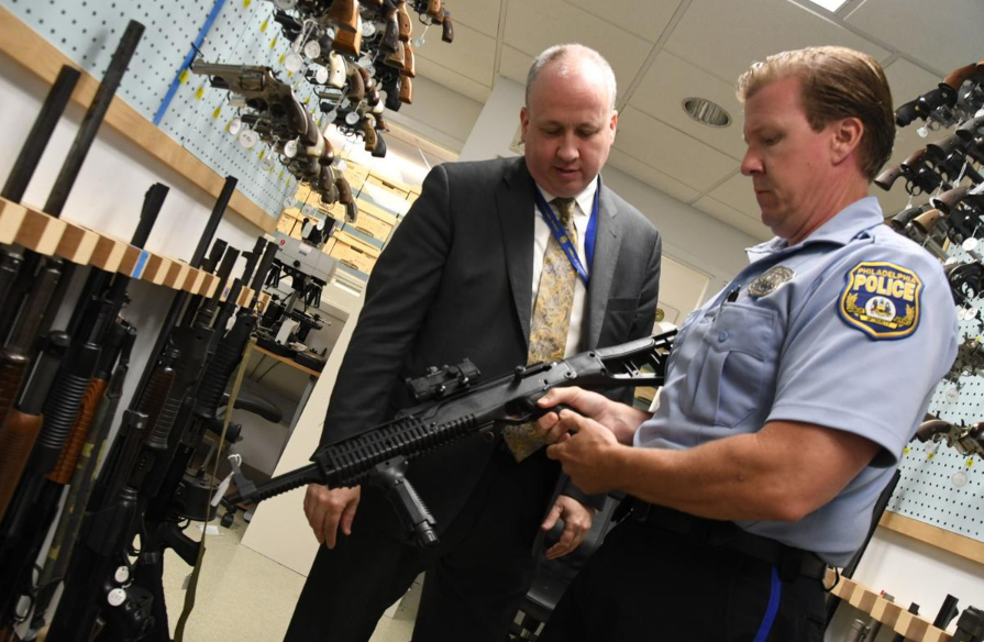 Screen Shot 2019-07-16 at 1.40.17 PM Philadelphia Police Officer Bob Mahan holds a firearm stored in the department's Forensic Science Center beside Michael Garvey, director of the Philadelphia Police Department's Office of Forensic Science (Abdul Sulayman/The Philadelphia Tribune)