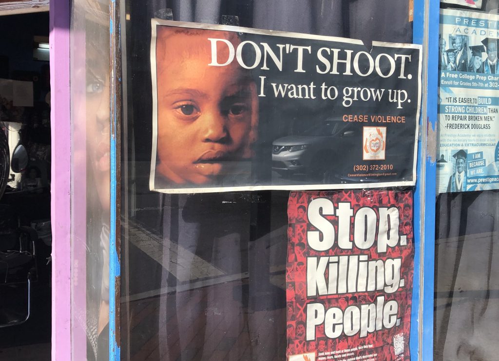 Stop Killing People posters on a barbershop window in downtown Wilmington