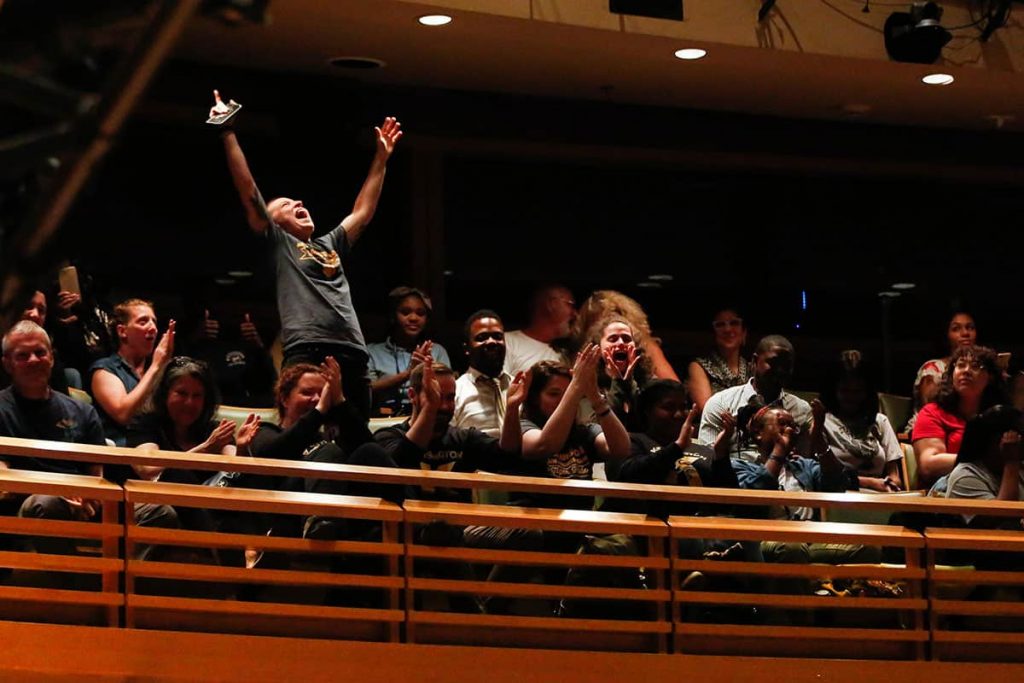 Tiger-Poets-13 KHSA English teacher Maddie Luebbert throws their hands up in celebration and cheers with other faculty, staff, and City Year leaders, as they learn that the Tiger Poets will advance to the second round at championships. (Photo by Maggie Loesch)