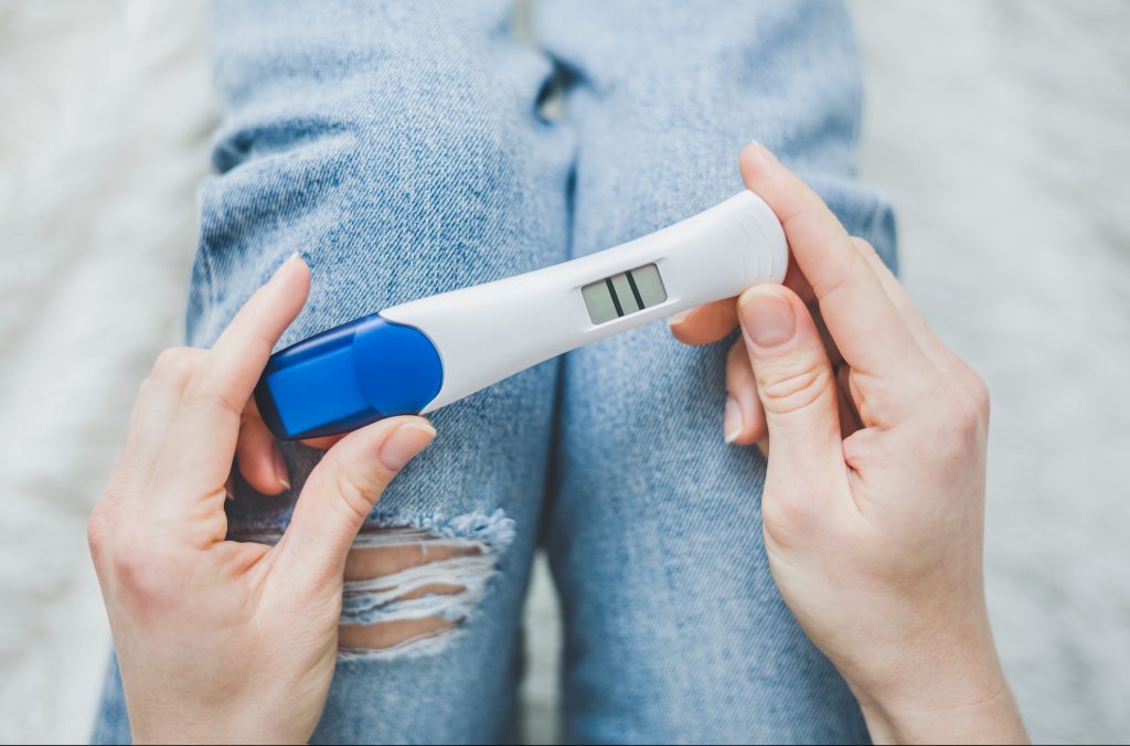 Young Woman Hoding On Jeans And Looking On Positive Pregnancy Te (Valeria_Aksakova/BigStock)