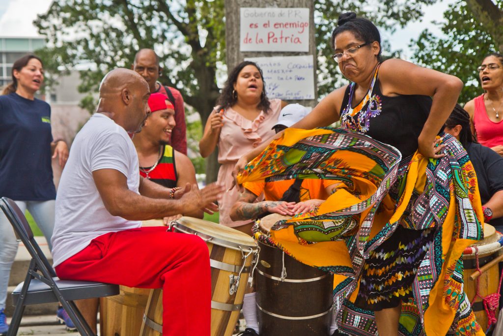 2019 08 2 k paynter puerto rician resignation celebration-3 Bomba drummer Jose Emmannuelli Nater plays for Rochel Rojas as she dances at the celebration of the resignation of Puerto Rican governor Ricardo Rosselló at Fairhill Square in Kensington. (Kimberly Paynter/WHYY)