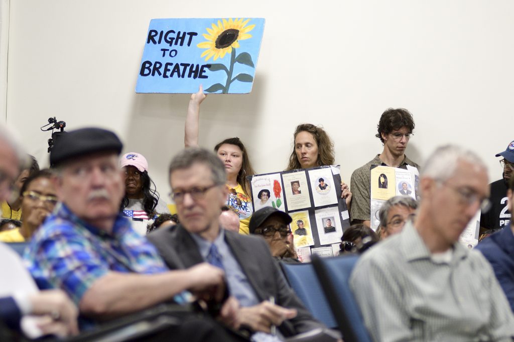 PES Meeting on Enviromental Issues Signs are held up as a standing room only crowd listens to testimony given by environmental experts, community activists and residents during a community meeting regarding the future of the site of Philadelphia Energy Solutions in August 2019. (Bastiaan Slabbers for WHYY)