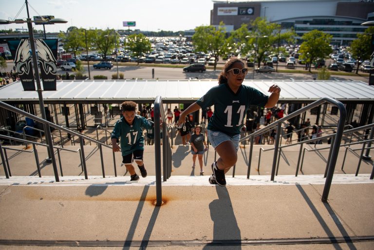 Isaac and Jazzy Dyer, from Harrisburg, Pa., run up the steps to Lincoln Financial Field before the start of open practice on Sunday, August 4, 2019. (Kriston Jae Bethel for WHYY)