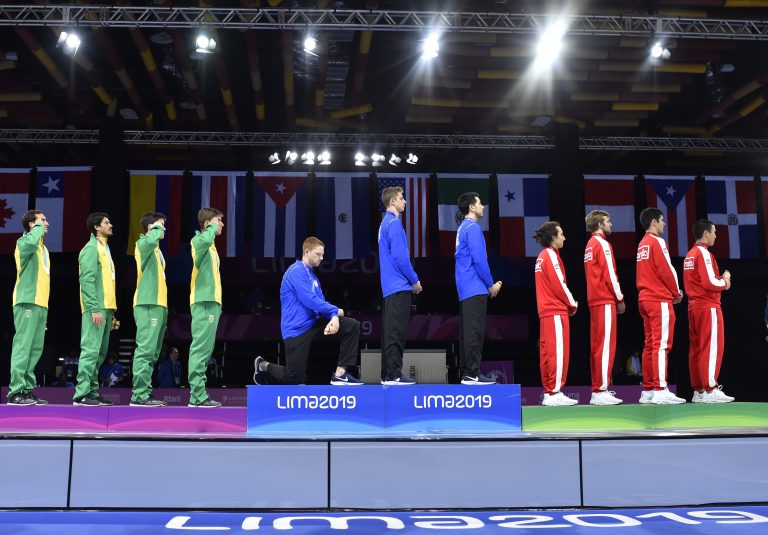 In this Friday, Aug. 9, 2019 photo, released by Lima 2019 News Services, Race Imboden of the United States takes a knee, as teammates Mick Itkin and Gerek Meinhardt stand on the podium after winning the gold medal in team's foil, at the Pan American Games in Lima, Peru. 'Racism, gun control, mistreatment of immigrants, and a president who spreads hate are at the top of a long list' of America's problems, Imboden said in a tweet sent after his medals ceremony. 'I chose to sacrifice my moment today at the top of the podium to call attention to issues that I believe need to be addressed.' (Jose Sotomayor/Lima 2019 News Services via AP)