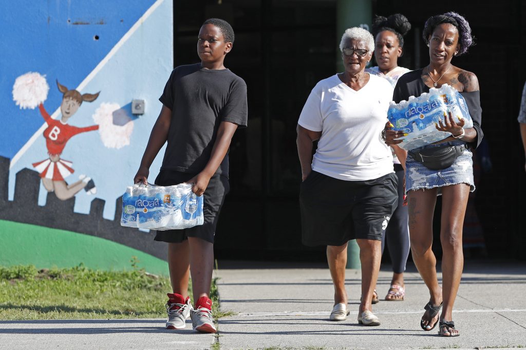 Newark Lead in Water Rahjiah McBride, of Chester, Pa., (right), helps her relatives, Newark residents Elnora and Bowdell Goodwin, center and second right, as Goodwin's son pitches in carrying bottled water from the Boylan Street Recreation Center, Monday, Aug. 12, 2019, in Newark, N.J. (Kathy Willens/AP Photo)