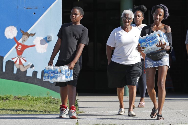 Rahjiah McBride, of Chester, Pa., (right), helps her relatives, Newark residents Elnora and Bowdell Goodwin, center and second right, as Goodwin's son pitches in carrying bottled water from the Boylan Street Recreation Center, Monday, Aug. 12, 2019, in Newark, N.J. (Kathy Willens/AP Photo)
