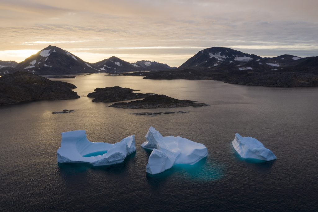 APTOPIX Greenland Glaciers On the Edge In this Aug. 16, 2019, photo, large Icebergs float away as the sun rises near Kulusuk, Greenland. Scientists are hard at work, trying to understand the alarmingly rapid melting of the ice. (AP Photo/Felipe Dana)