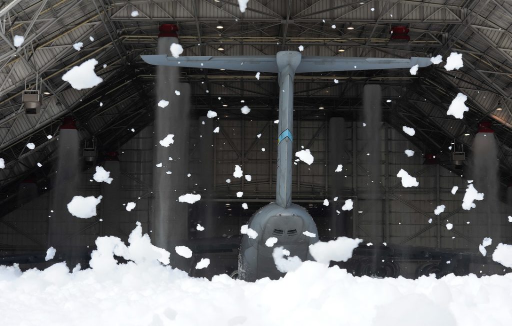 Firefighting foam at Dover AFB, Del. Wind-blown clumps of fire-suppression foam hang in the air outside of hangar 706 while the tail of a massive C-5M Super Galaxy can be seen inside the hangar at Dover Air Force Base, Del. (U.S. Air Force photo/Greg L. Davis)