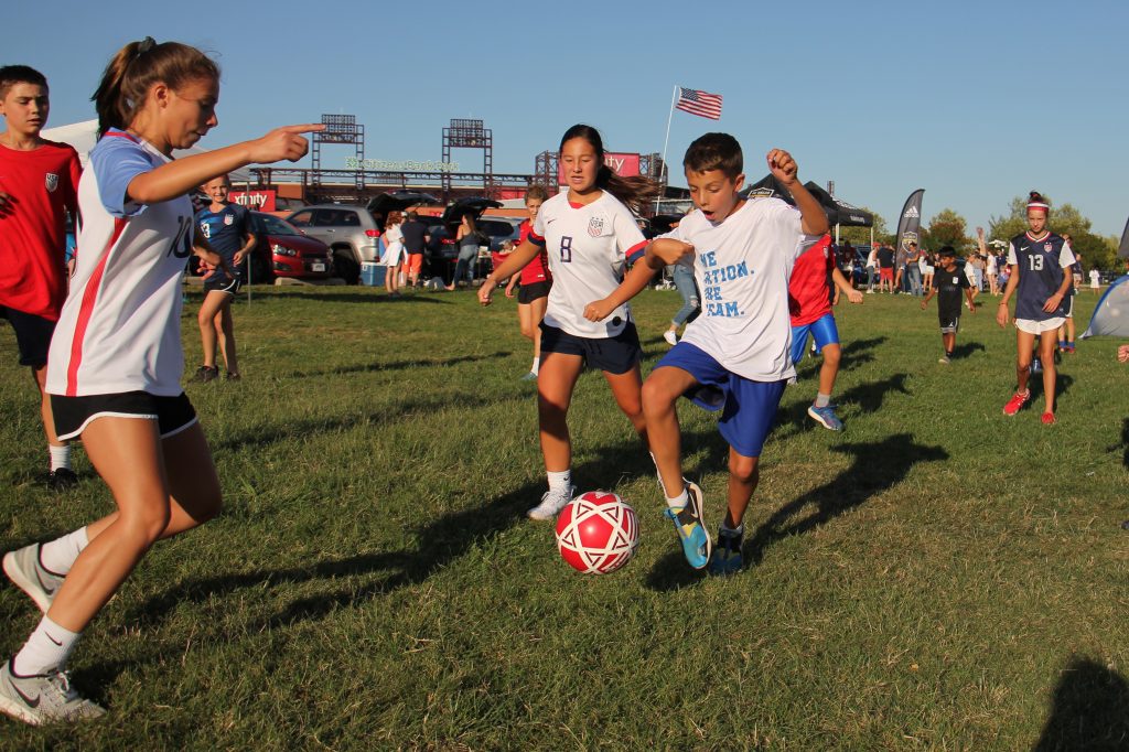Image uploaded from iOS (2) Young soccer fans play pickup games on the grass outside Lincoln Financial Field while waiting for the start of the U.S. Women’s soccer game against Portugal. (Emma Lee/WHYY)