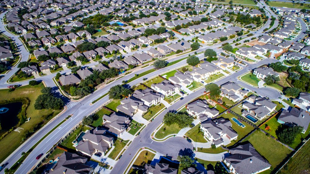 Aerial Drone View High Above Modern Suburbia With Lots Of Concre (Photo Bigstock)
