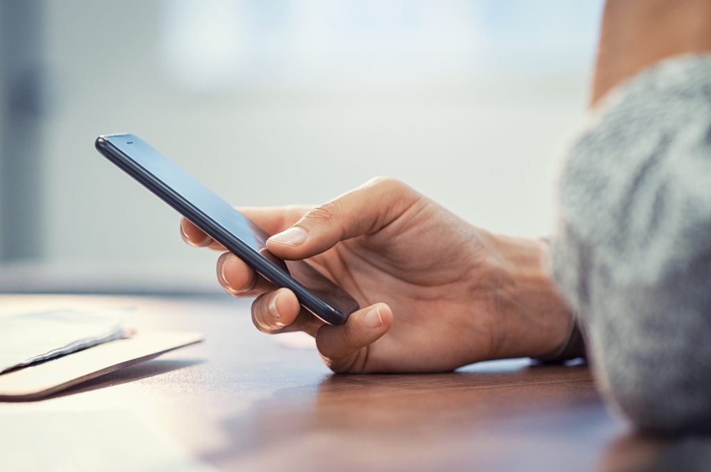 Closeup hand of woman using smartphone on wooden table. Business Little is known about how our brain processes text messages. (BigStock/Rido81)