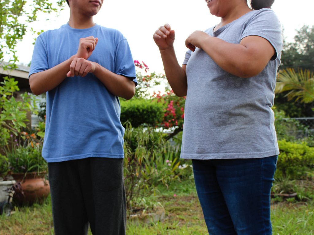A Guatemalan teen asylum-seeker (left), who isn't able to hear or speak, signs with his mom in Florida. He was brusquely separated from her and held in a shelter for nearly three months, unable to readily communicate, according to a civil rights complaint filed with the Department of Homeland Security. (Susan Ferriss/Center for Public Integrity)