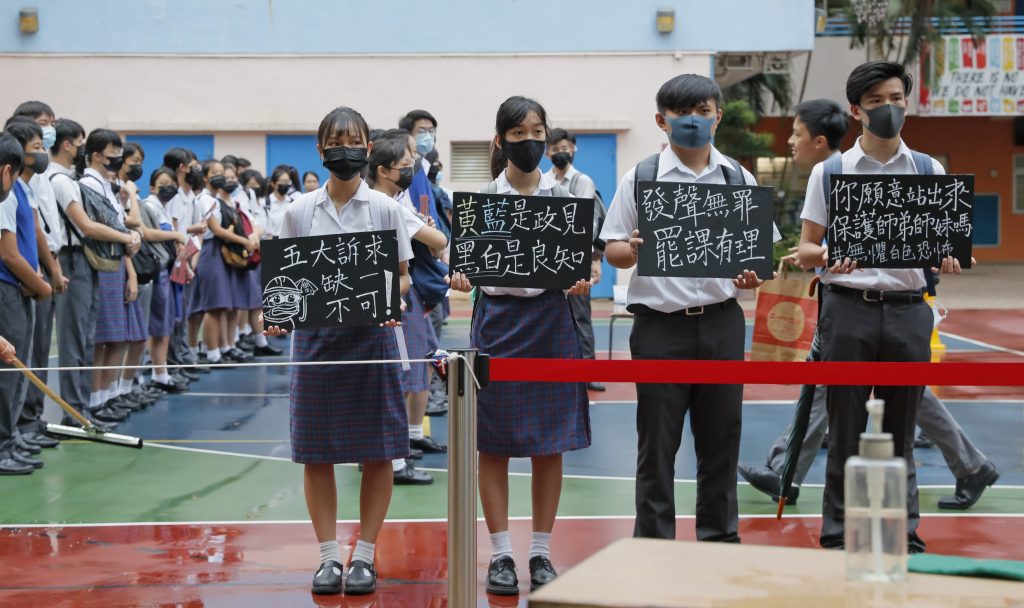 High school students wearing masks, hold placards which read “Five key demands are indispensable,” as they continue their school boycott in Hong Kong on Wednesday. High school students wearing masks, hold placards which read