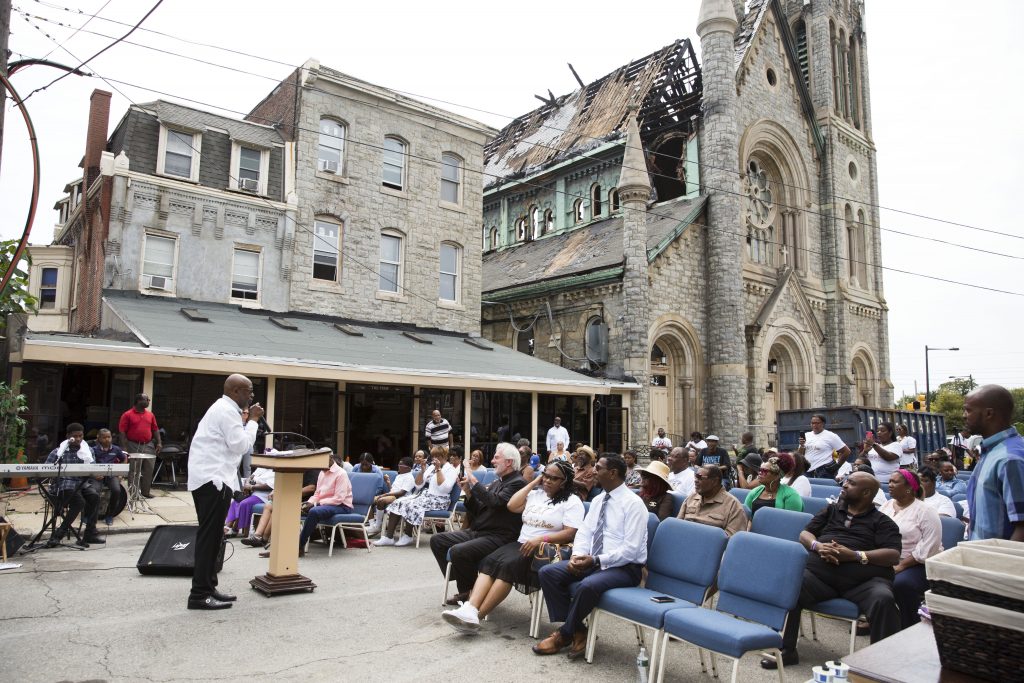 2019 09 01-r wisniewski-Bishop Benjamin F Peterson Jr-west philly greater bible way temple fire-3 Bishop Benjamin Peterson Jr. (left) leads Sunday morning services outside of the damaged Greater Bible Way Temple on Sept. 1, 2019. (Rachel Wisniewski for WHYY)