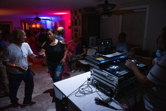 Guests dance from the kitchen to the living room at a viejoteca in Oxford Circle on Sunday, September 15, 2019. (Kriston Jae Bethel for WHYY)