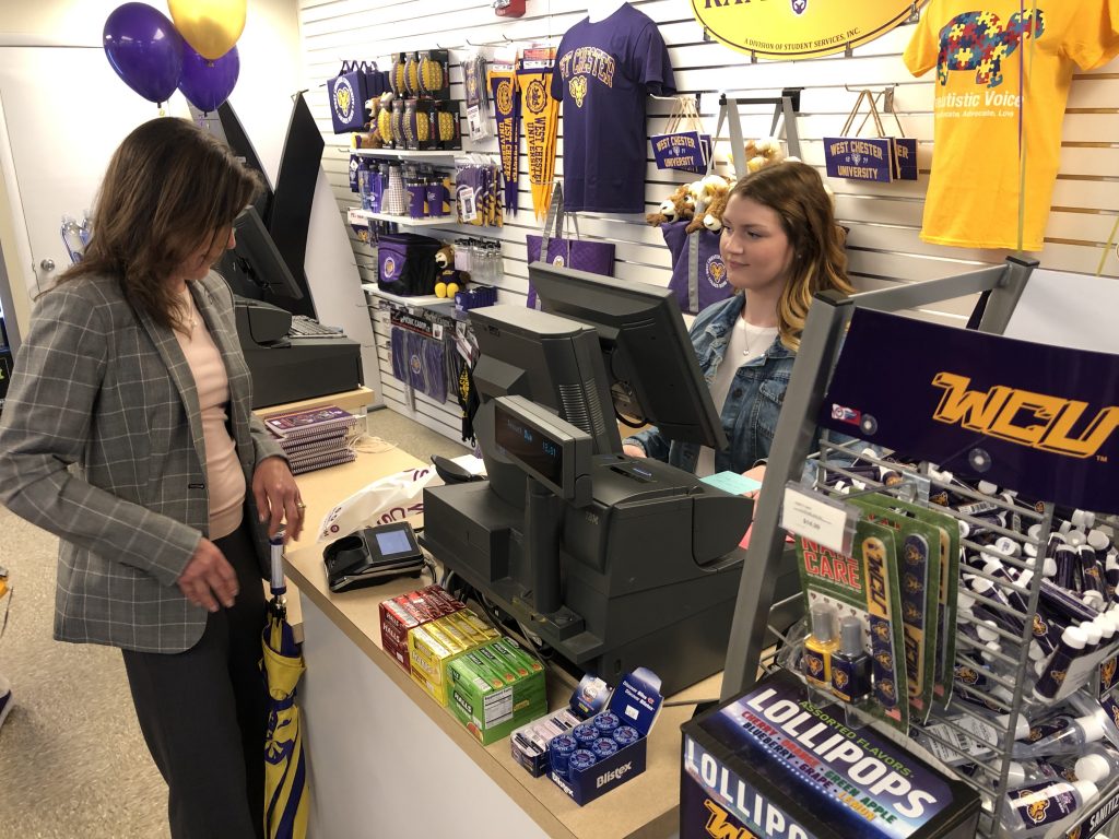 IMG_0509 Monica Zimmerman, executive director of West Chester University’s Entrepreneurial Leadership Center, purchases a travel mug from The Ram Shop at the edge of campus. WCU student Madeline Berger rings up the transaction. (P. Kenneth Burns/WHYY)