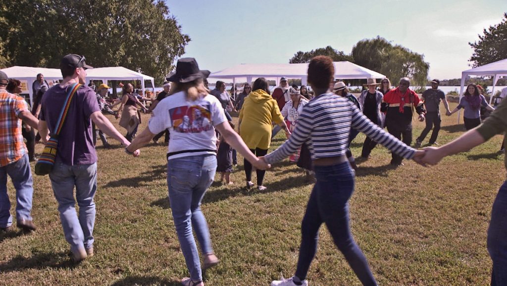 2019 10 11 k paynter indigenous peoples’ day 2019-4 Dancers from the Nanticoke Lenni-Lenape tribe join hands with spectators at the 2019 Indigenous Peoples’ Day celebration at Penn Treaty Park in Philadelphia. (Kimberly Paynter/WHYY)