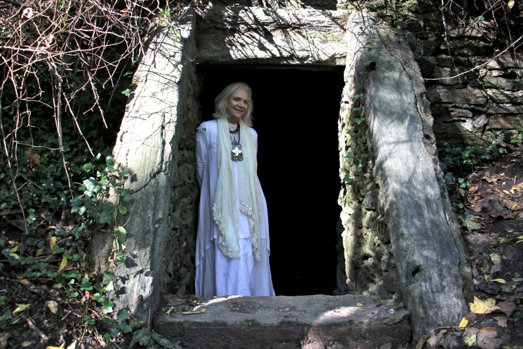 Kris Soffa, a trail ambassador for the Friends of the Wissahickon, stands in the entrance to the Cave of Kelpius. (Emma Lee/WHYY)