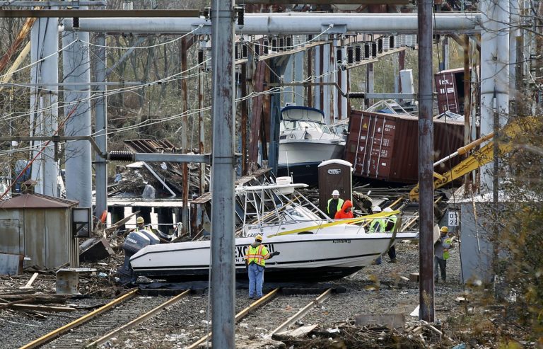 In this Oct. 31, 2012 file photo, workers try to clear boats and debris from the New Jersey Transit's Morgan draw bridge after surge from Sandy pushed boats and cargo containers onto the train tracks. (Mel Evans/AP Photo, File)