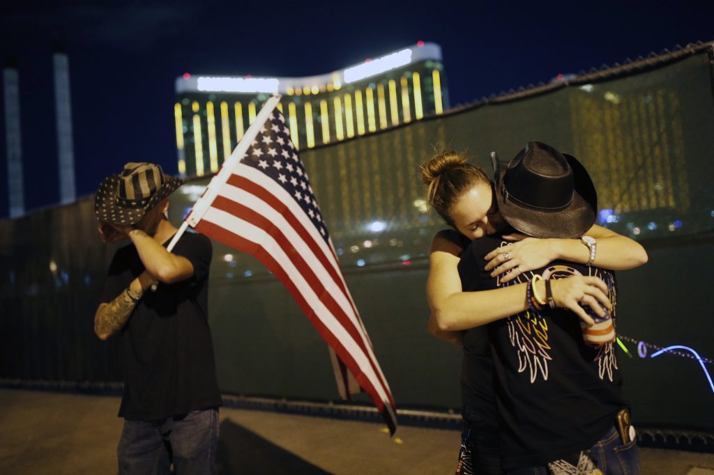 Las Vegas Shooting Anniversary Megan Murphy, right in hat, embraces Cara Knoedler as Kenneth Wright wipes his eyes on the first anniversary of the mass shooting in Las Vegas. Behind them is the site of the shooting. (John Locher/AP Photo)