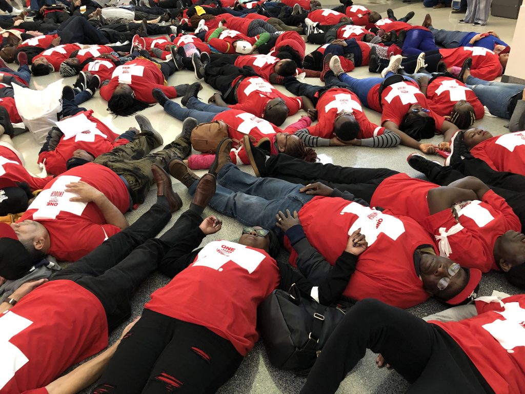 IMG_0943 Food prep workers die-in at the Philadelphia airport on Wednesday night to demonstrate the life and death stakes of lacking affordable healthcare. (Nina Feldman/WHYY)