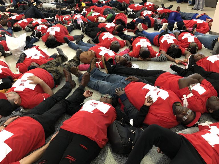 Food prep workers die-in at the Philadelphia airport on Wednesday night to demonstrate the life and death stakes of lacking affordable healthcare. (Nina Feldman/WHYY)