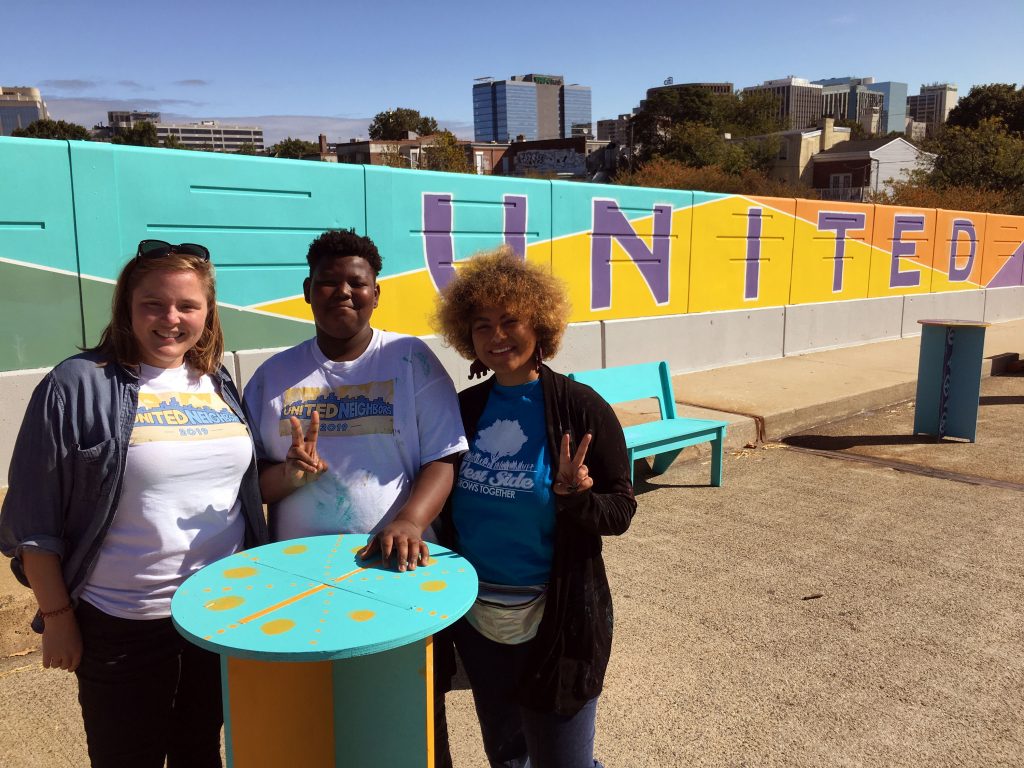 IMG_5524 West Side Grows Together's Sarah Lester, volunteer Brenden Cephas and United Neighbors organizer Vanity Constance stand in front of a mural on the Seventh Street bridge over I-95. (Mark Eichmann/WHYY)