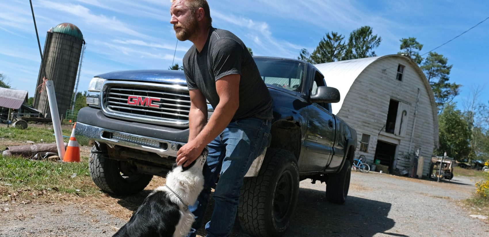 Grain farmer Jesse Poliskiewicz pets a dog while visiting his father's farm Sept. 20, 2019, in Upper Mount Bethel Township, Pennsylvania. (Matt Smith for Keystone Crossroads)