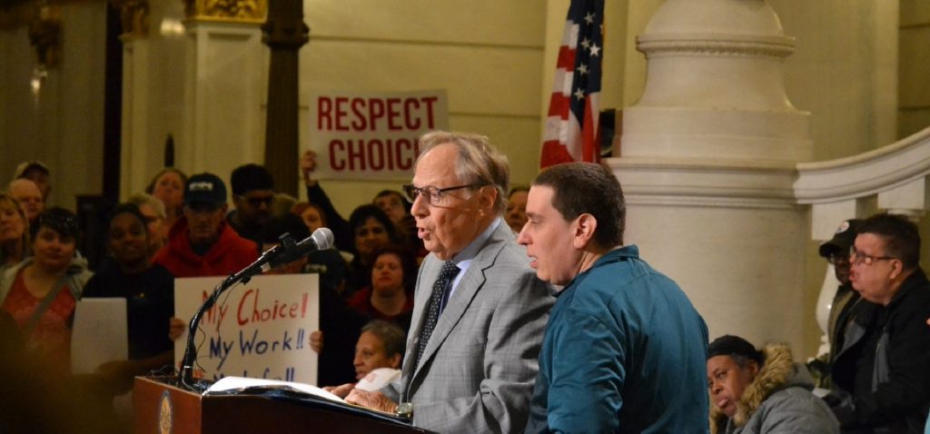 Schwartz1-e1571955867112-1920×897 Philadelphia-based attorney Theodore Schwartz, at left, talks at a rally for people with intellectual disabilities. At right is his son, Scott (Brett Sholtis/Transforming Health)
