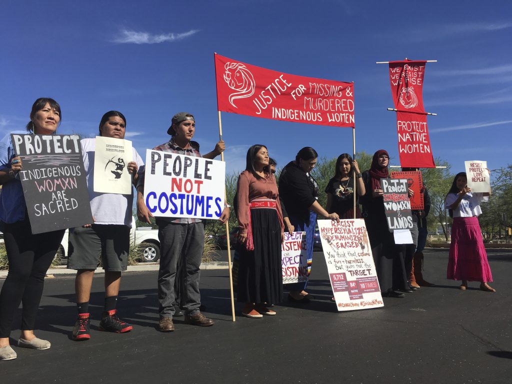 Native American protesters stand outside the Phoenix office of a retailer of “sexy Native American” costumes last year. For some ethnic and racial groups, Halloween has long been haunted by costumes that perpetuate stereotypes and instances of cultural appropriation. Native American protesters stand outside the Phoenix office of a retailer of