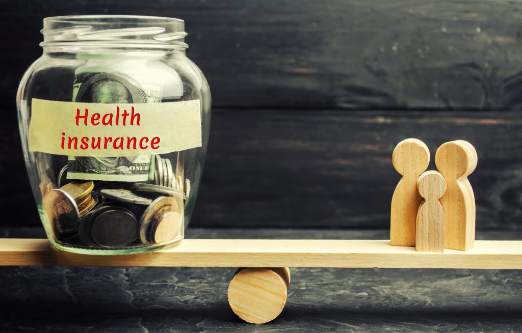 Glass Jar With Money And The Words “health Insurance” And The Fa (Bigstock/ilixe48)