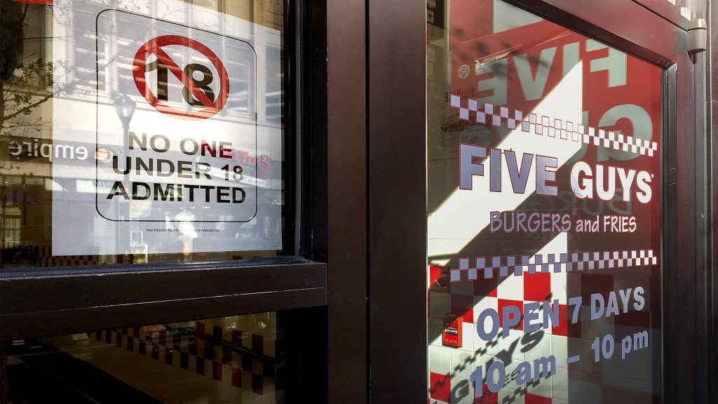 A sign in the door of a Center City Five Guys bans kids under 18 from entry (Michaela Winberg/Billy Penn )