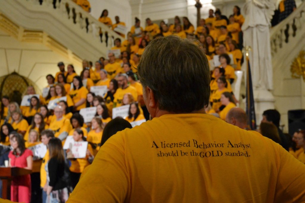 man1-1920×1280 Supporters of House Bill 1900 wore gold shirts at a rally in the state Capitol Wed., Oct. 23, 2019. They want the state to license applied behavior analysis as a medical profession so that insurance will cover it. (Brett Sholtis/Transforming Health)