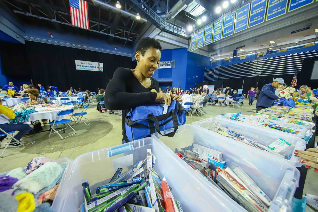 Volunteer Nina Parker packs a duffel full of supplies during Kind to Kids Foundation’s 4th Annual My Blue Duffel Community Service Day. (Saquan Stimpson for WHYY)