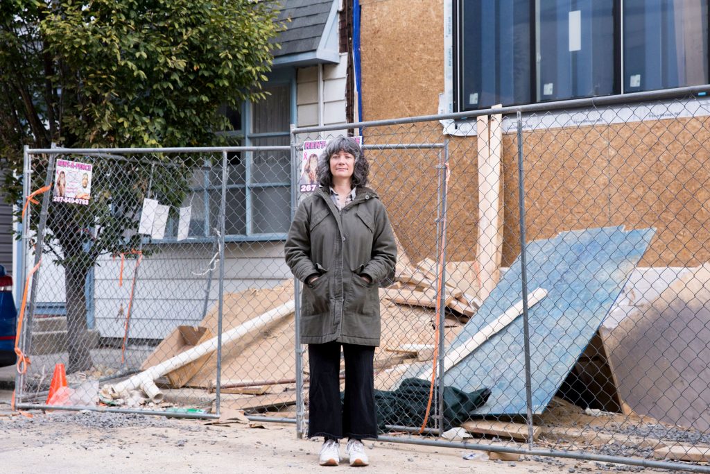 2019-11-05-r-wisniewski-Sara-Gallo-fishtown-house-damage_03-rs Sara Gallo stands between her home and the new construction next door on November 5, 2019. Due to the demolition and rebuilding of the twin house adjoining hers, her home now suffers structural issues, settling, and leaking. (Rachel Wisniewski for WHYY)