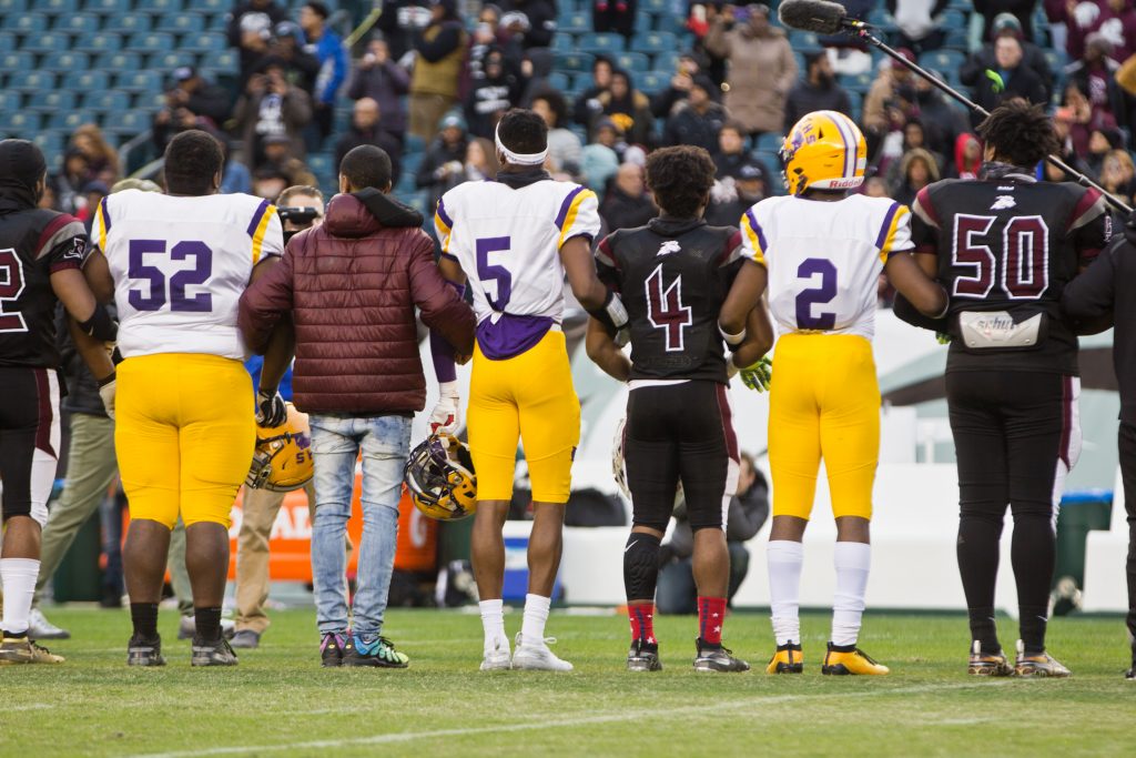 2019 11 20 k paynter pleasantville vs camden at the linc-8 Members of the Camden Panthers and the Pleasantville Greyhounds link arms during a moment of silence for 10 year-old, Micah Tennant, who was shot during a high school football game last week. The game resumed Wednesday at Lincoln Financial field. (Kimberly Paynter/WHYY)