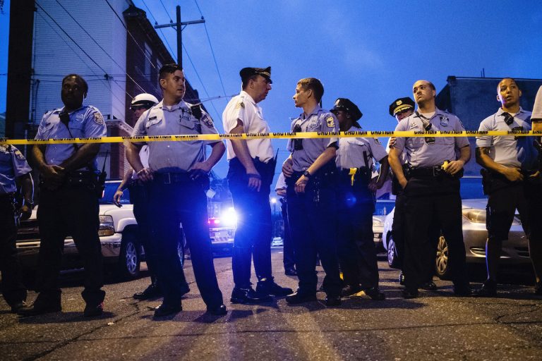 Officers gather for crowd control near a massive police presence set up outside a house as they investigate a shooting in Philadelphia, Wednesday, Aug. 14, 2019. (AP Photo/Matt Rourke)