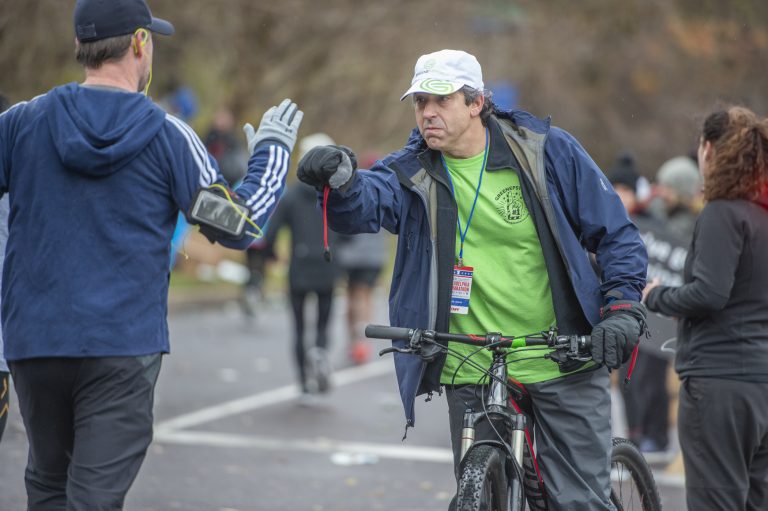 At the 18 mile mark, Mitchell Greene fist bumps a runner during the 2019 Phialdelphia Marathon. (Jonathan Wilson for WHYY)
