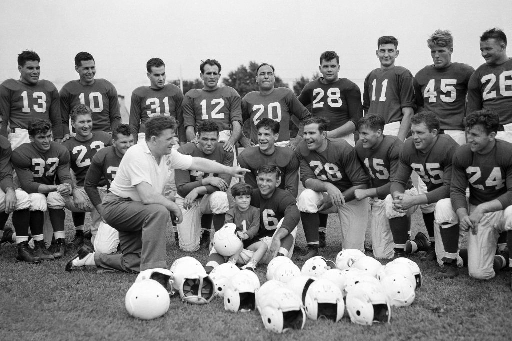 NFL At 100 The 1930s In this July 26, 1939, file photo, Philadelphia Eagles owner and head coach Bert Bell talks to his squad as his son, Bert Bell Jr. sits on a players lap, in Philadelphia. Bell, who later became the league's commissioner, created the NFL draft as a way to assist teams who couldn't attract top talent in the free-for-all system that had been in place. (AP Photo/File)