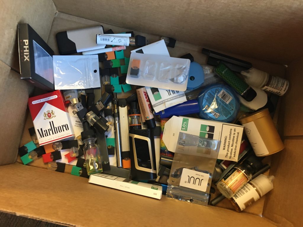 A box of vaping products confiscated from students or thrown away at Boulder High School. The school’s assistant principal collects items for later delivery to the county’s hazardous waste facility. A box of vaping products confiscated from students or thrown away at Boulder High School. The school's assistant principal collects items for later delivery to the county's hazardous waste facility. (John Daley/Colorado Public Radio)